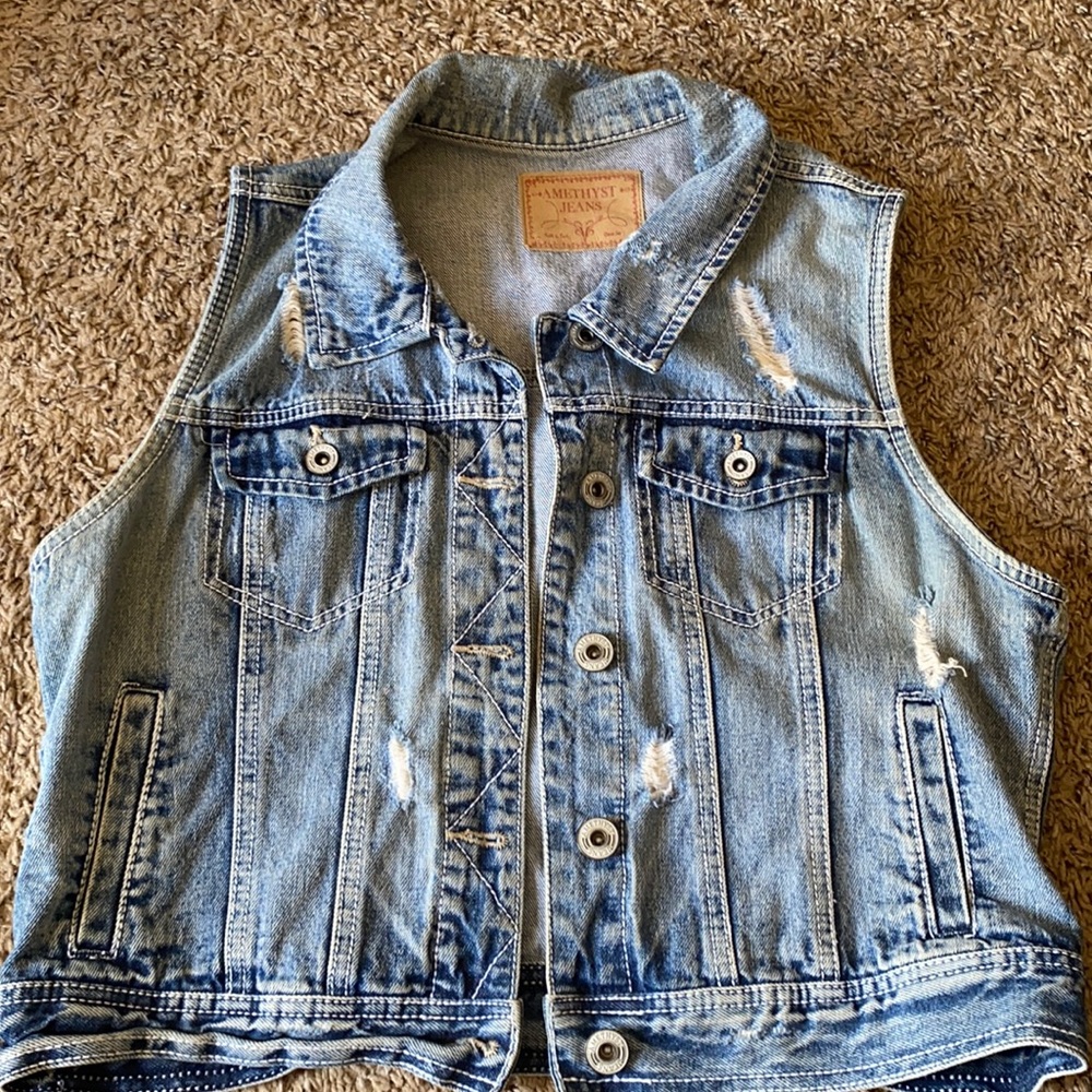 Sleeveless jean jacket. The brand is amethyst jeans and it’s a light wash denim